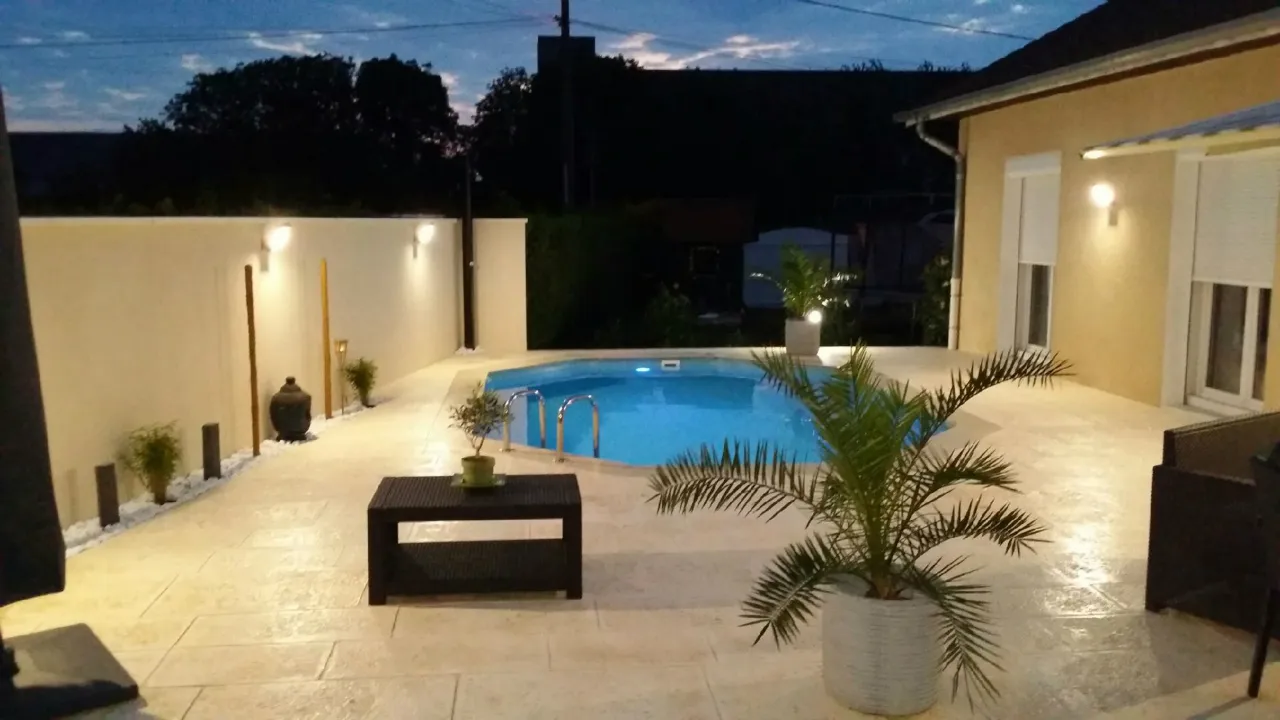 Terrasse et plage de piscine en béton imprimé éclairées en soirée